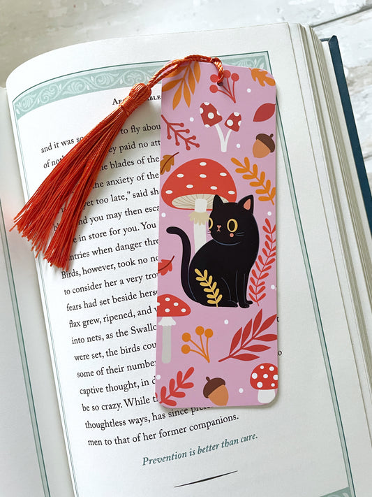 Adorable kawaii black cat with big eyes, surrounded by autumn leaves, perched on a cozy bookmark. Perfect for adding a touch of fall charm to your reading