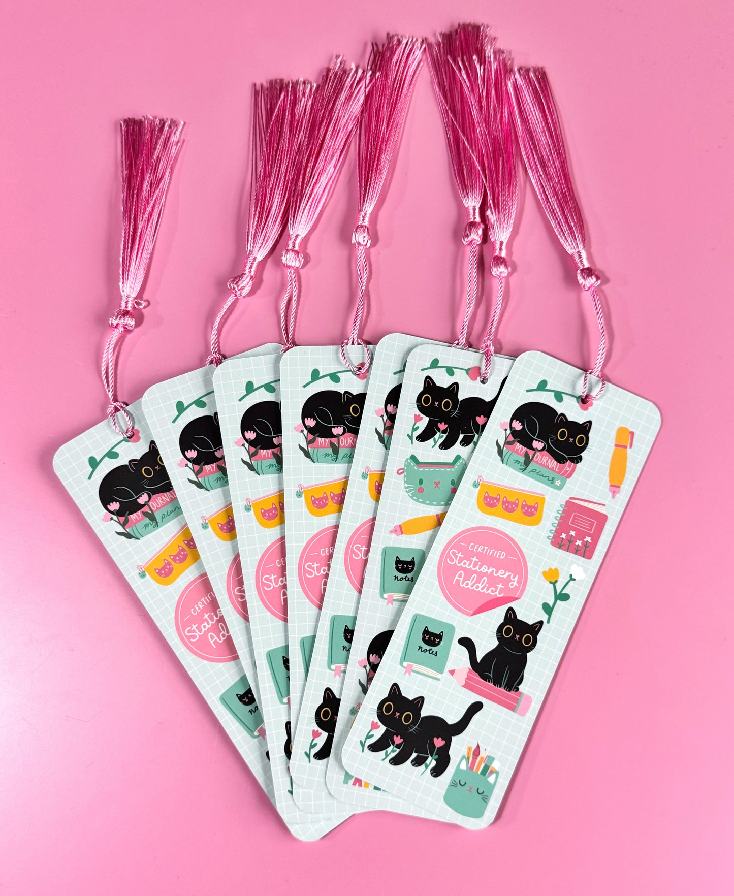 Cute cat bookmark with pink tassel, featuring various stationery icons.