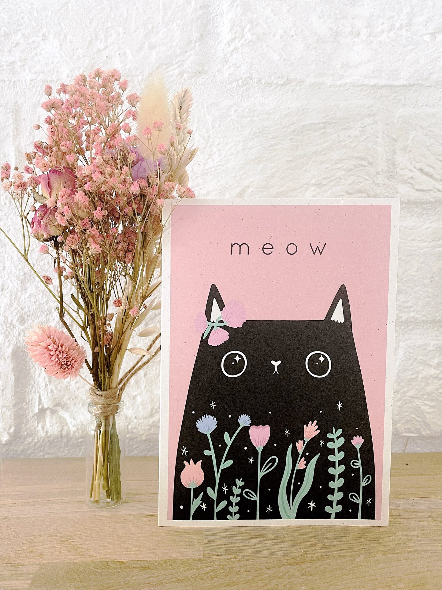 Pink cat greeting card featuring a black cat with 'Meow' text, displayed next to a vase of dried flowers, eco-friendly and perfect for cat lovers or birthday gifts