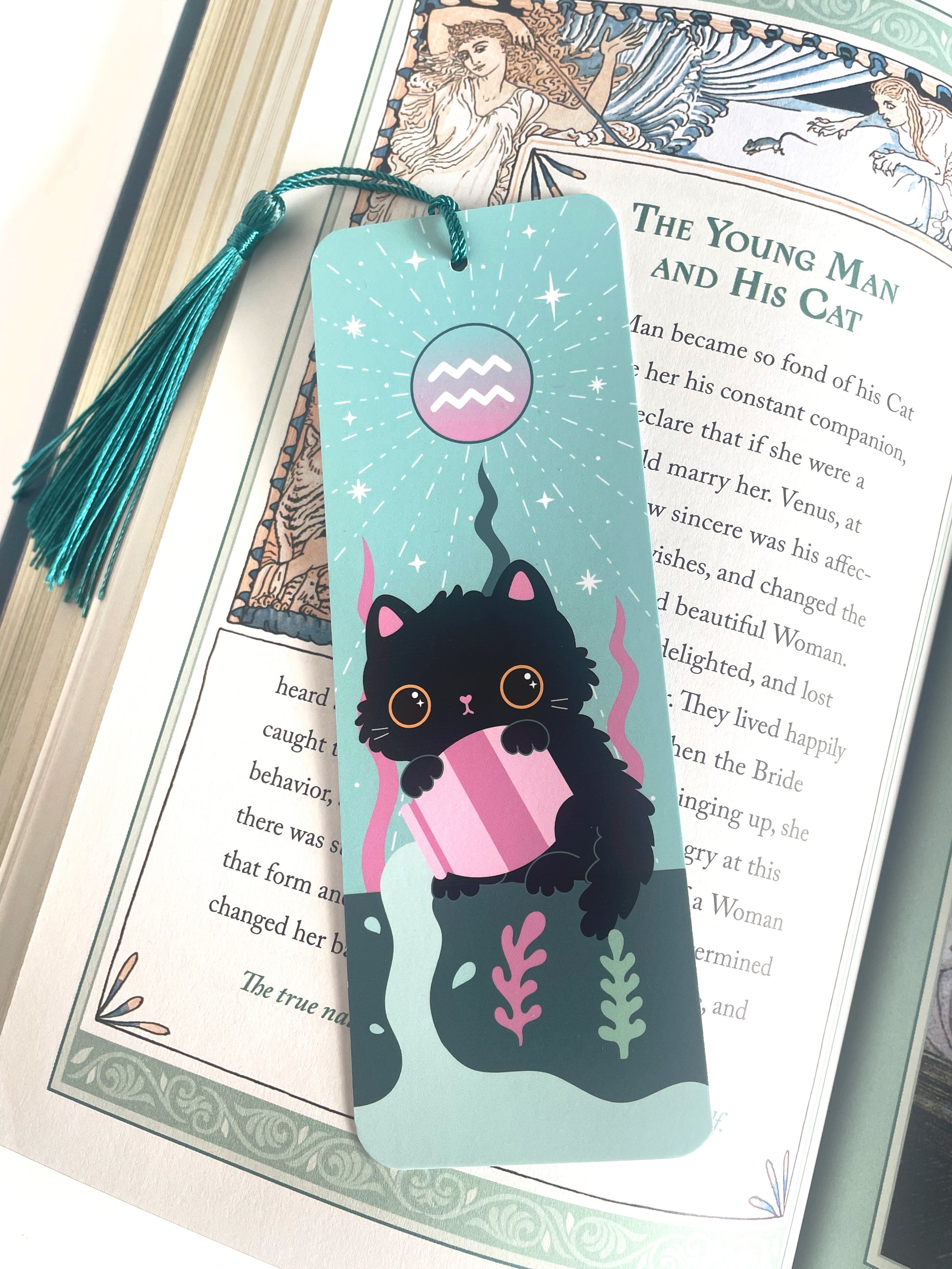 Aquarius cat bookmark with cute tassel placed in an open book, perfect for cat lovers and Aquarius astrology fans