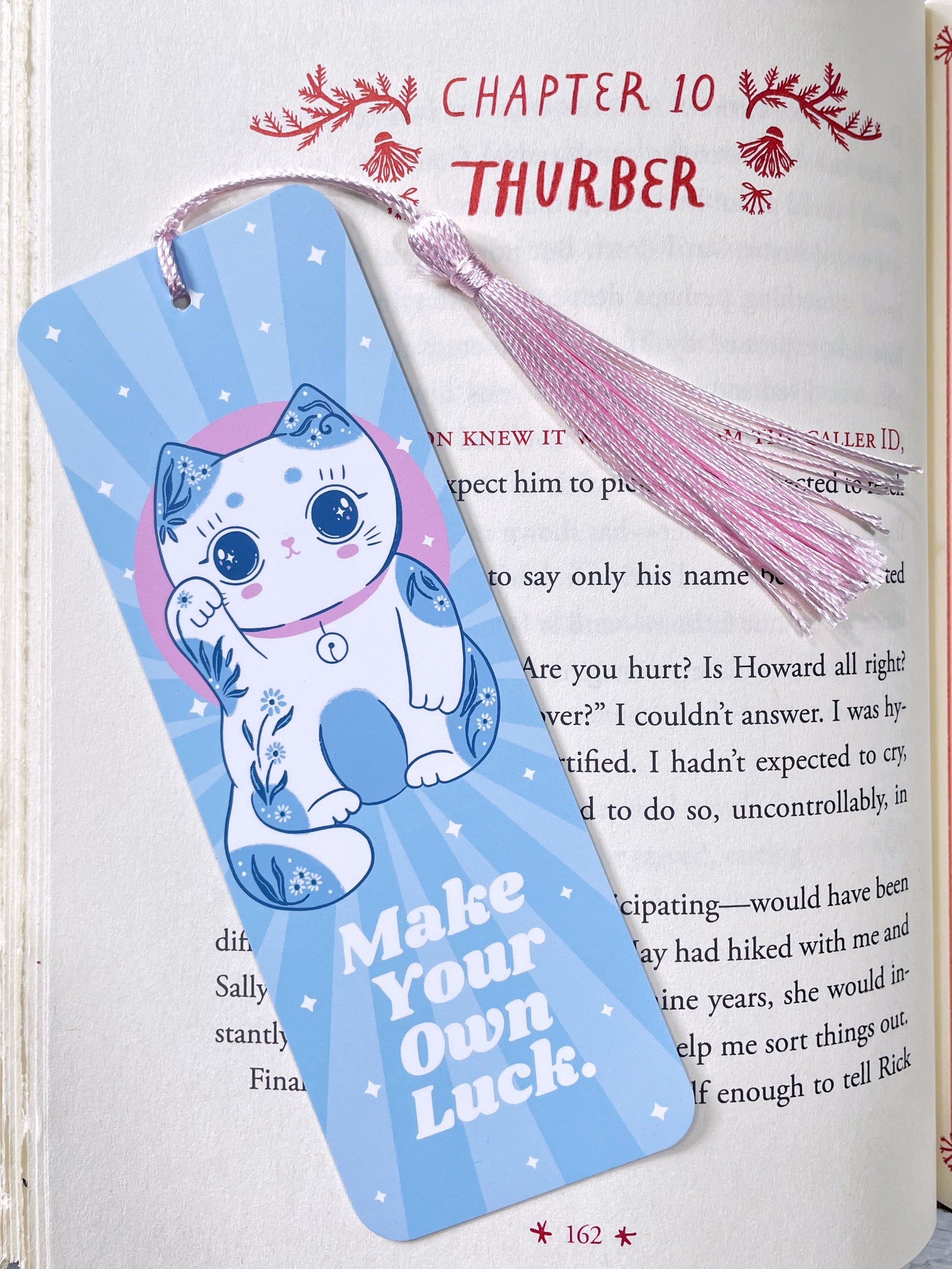 Light blue lucky cat bookmark with pink tassel, featuring the phrase 'Make Your Own Luck,' perfect for kawaii style lovers and book lovers.