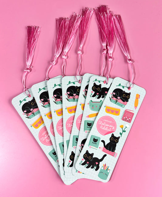 Cute cat bookmark with pink tassel, featuring various stationery icons.