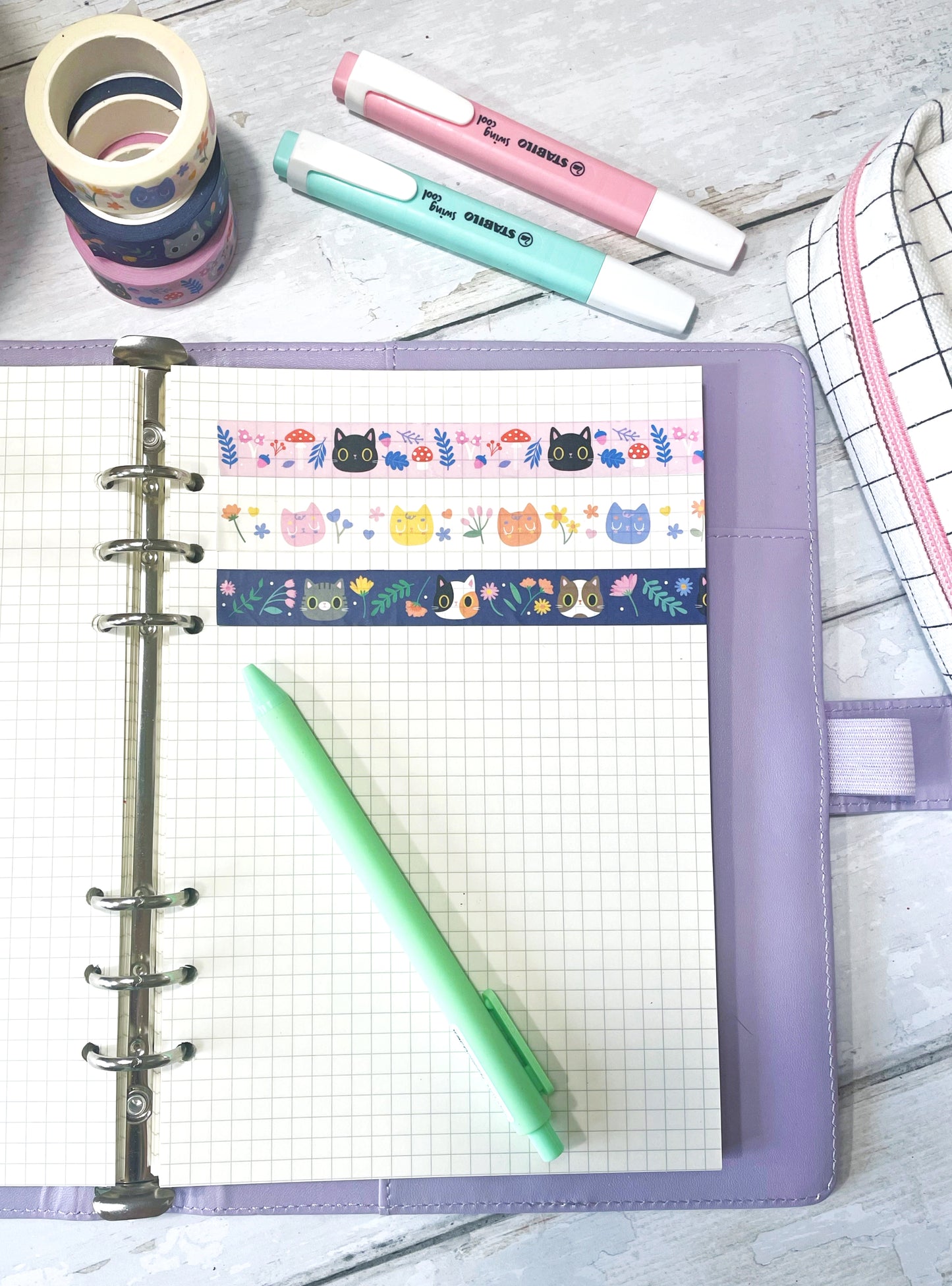 Various washi tapes including cute cat and floral designs, placed in a bullet journal, perfect for journaling and scrapbooking